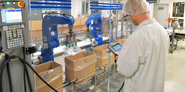 a medical manufacturing worker examine cardboard boxes being filled with medical supplies